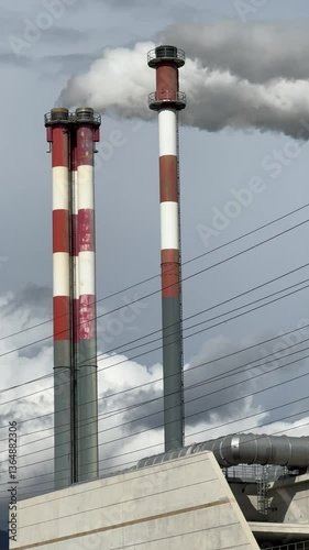 Dense smoke flowing from Chimneys of the incineration plant against cloudy sky