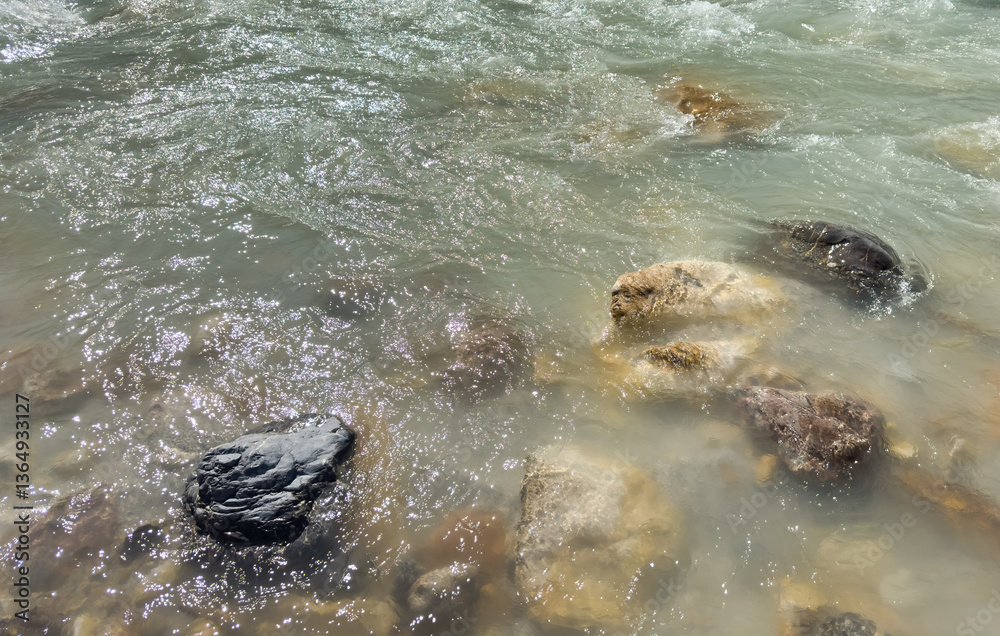 Obraz premium mountain river flowing over assorted rocks. soft water movement with shimmering reflection. natural texture. abstract nature background, nature design, eco