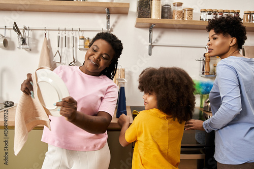 Tableau sur toile Loving family shares joyful moments while doing dishes in a cozy kitchen