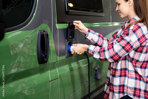 Woman connecting charging cable to power input port on Recreational Vehicle to recharge batteries