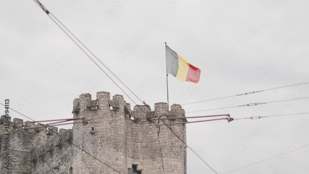 Bandiera Belga che svetta su una torre , ripresa dal basso, durante una giornata nuvolosa. Città Europea