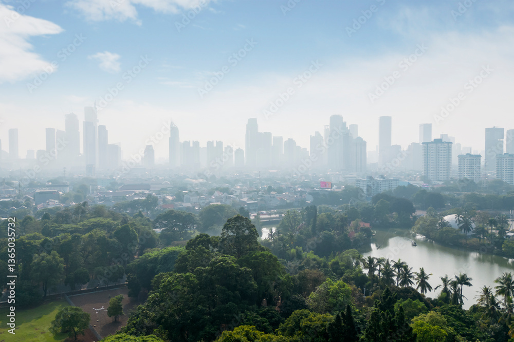 Obraz premium Aerial View of a Modern City Skyline with Green Park and River in the Foreground on a Hazy Morning