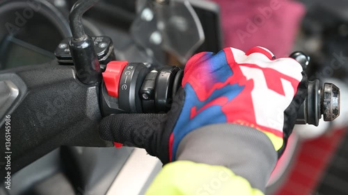 Footage of the biker putting his hand on the gas handle on the motorcycle and pressing the high beam button