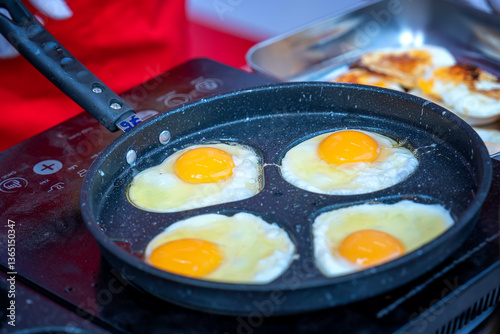 Closeup of four hen eggs being fried in a pan