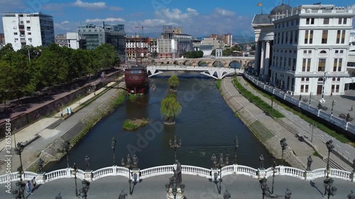 Drone retreating on Vardar River in Skopje City Centre with reveal of Art Bridge - Skopje, Macedonia photo