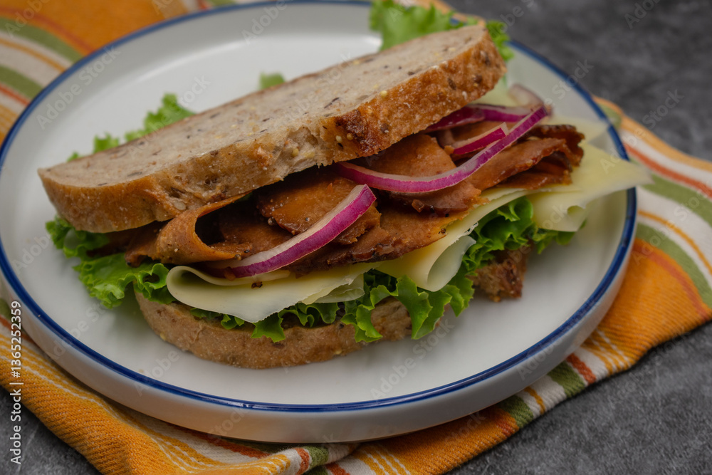 Obraz premium Plant based sandwich made with seitan, onion slices, vegan cheese, lettuce and seasoning