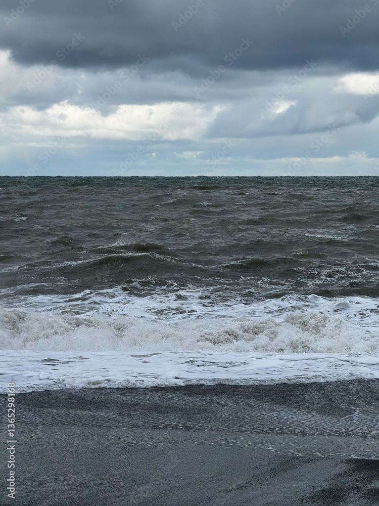 Rough ocean waves crashing under a dark cloudy sky