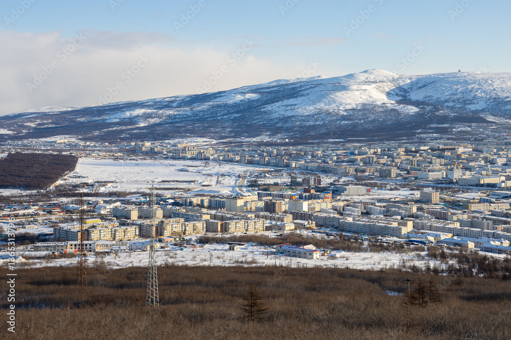 City of Magadan, Magadan Region, Russian Far East. Winter cityscape. View from above on a large northern city. Snow-capped mountains in the background. Cold weather.
