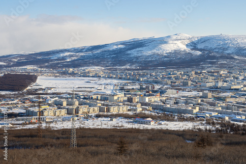 Obraz na płótnie City of Magadan, Magadan Region, Russian Far East. Winter cityscape. View from above on a large northern city. Snow-capped mountains in the background. Cold weather. w salonie