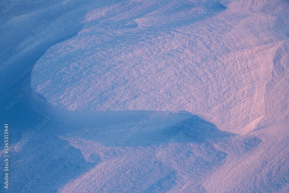 Beautiful winter background with snowy ground. Natural snow texture. Wind sculpted patterns on snow surface.