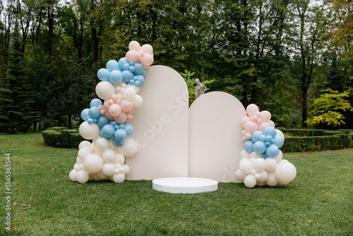 Luxury arch photo zone for gender party with blue and pink balloons on a park background with green grass