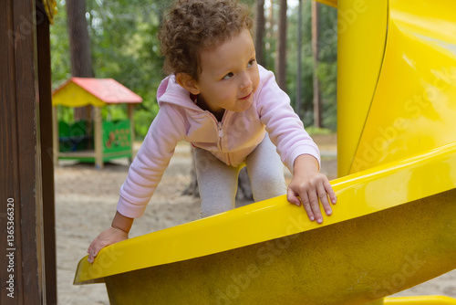 A sweet little child with curly hair on the playground