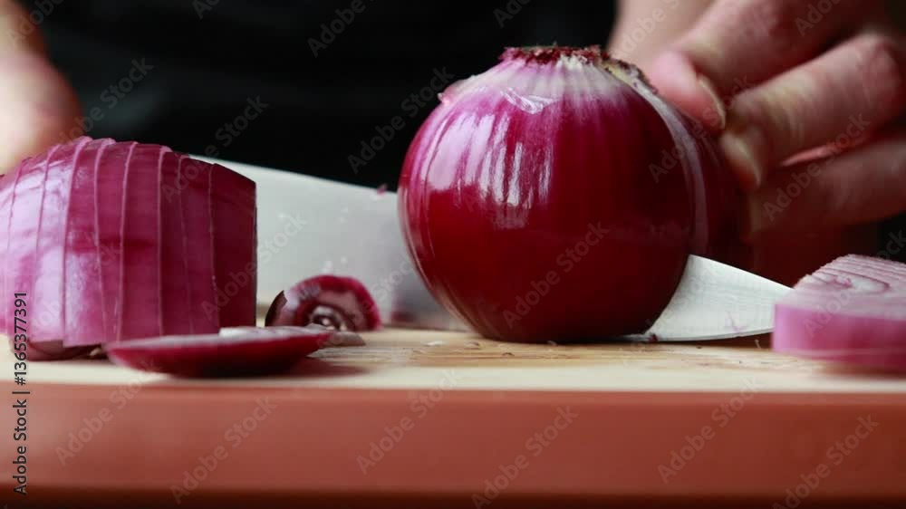 woman slicing red onion on wooden cutting board close-up