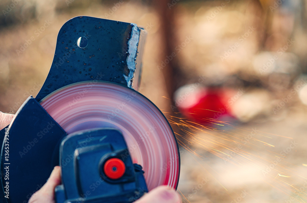 Obraz premium Hand using angle grinder to cut metal with sparks in construction site