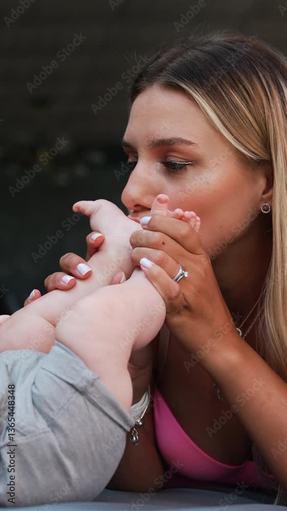 Loving mom kissing her infant son's tiny feet. Mother spending time with her child outdoors. Vertical video Loving mom kissing her infant son's tiny feet. Mother spending time with her child outdoors. Vertical video