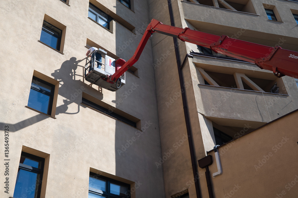 A man working at height on a basket lift on the facade of a building