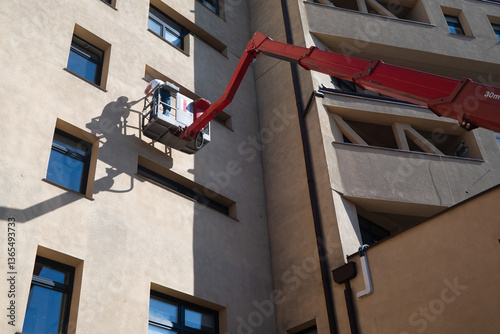 Obraz na płótnie A man working at height on a basket lift on the facade of a building w salonie