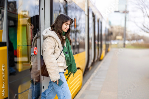 Tableau sur toile Young woman getting off the tram at a stop in the city