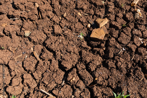 Crack in waterless pond, drying out. Waterless brown land with cracked soil in dry weather