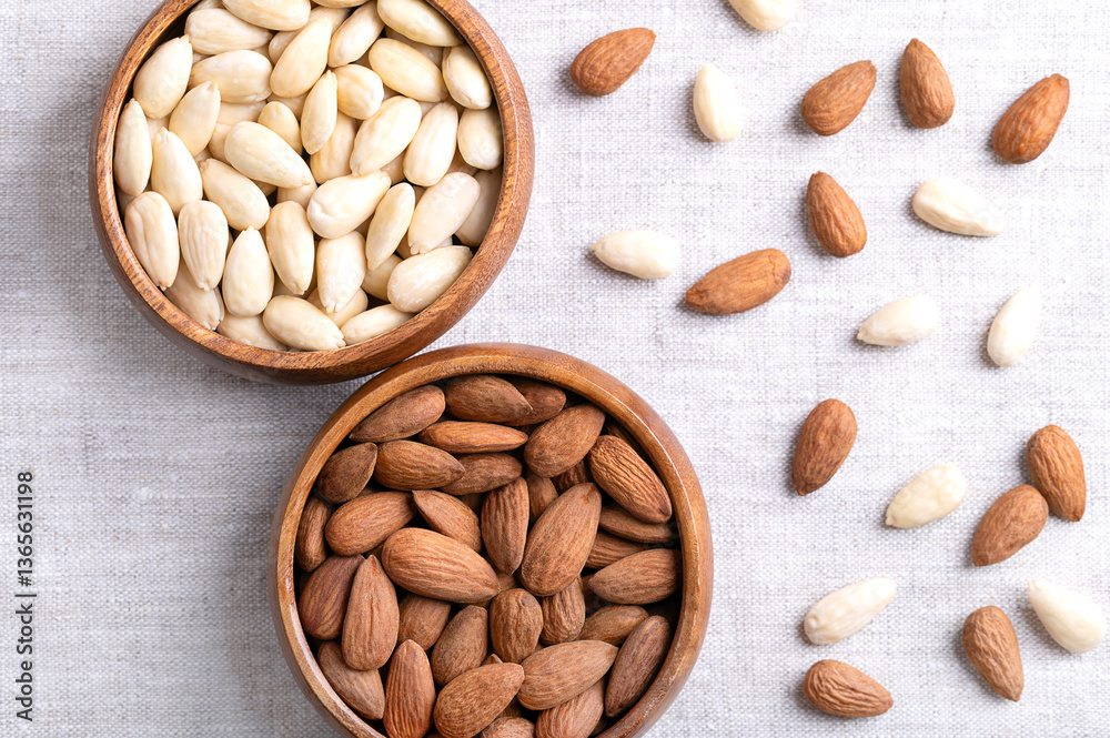 Almonds, with seed coats and blanched, in wooden bowls, on linen fabric. Fruits of Prunus amygdalus, syn. Prunus dulcis, ready-to-eat as snack or as ingredient for baking. Close up from above. Photo Almonds, with seed coats and blanched, in wooden bowls, on linen fabric. Fruits of Prunus amygdalus, syn. Prunus dulcis, ready-to-eat as snack or as ingredient for baking. Close up from above. Photo