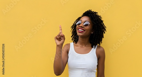 A radiant Black woman with a brilliant idea, joyfully pointing upwards against a sunny yellow backdrop.