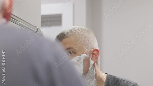 Reflection in the mirror of the man shaving. Self care