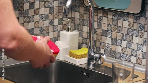 Man cleaning and polishing the kitchen faucet. Household