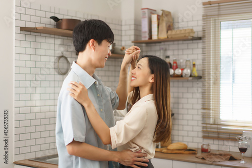 Happy young couple teasing and smiling at each other in cozy kitchen environment