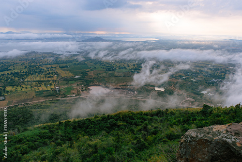 Vista of the Land: A breathtaking landscape unfolds beneath a dramatic sky. The expansive scene features rolling hills, shrouded in a veil of mist, with a sense of serene tranquility.