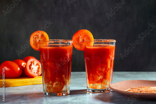 Two Bloody Mary cocktails in glass served with tomato slice and salt on dark background. Red cocktail. Alternative taste. Dirty dump drink