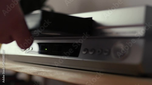Close up of a hand puting a videotape into video player. Retro vhs cassete in a player.