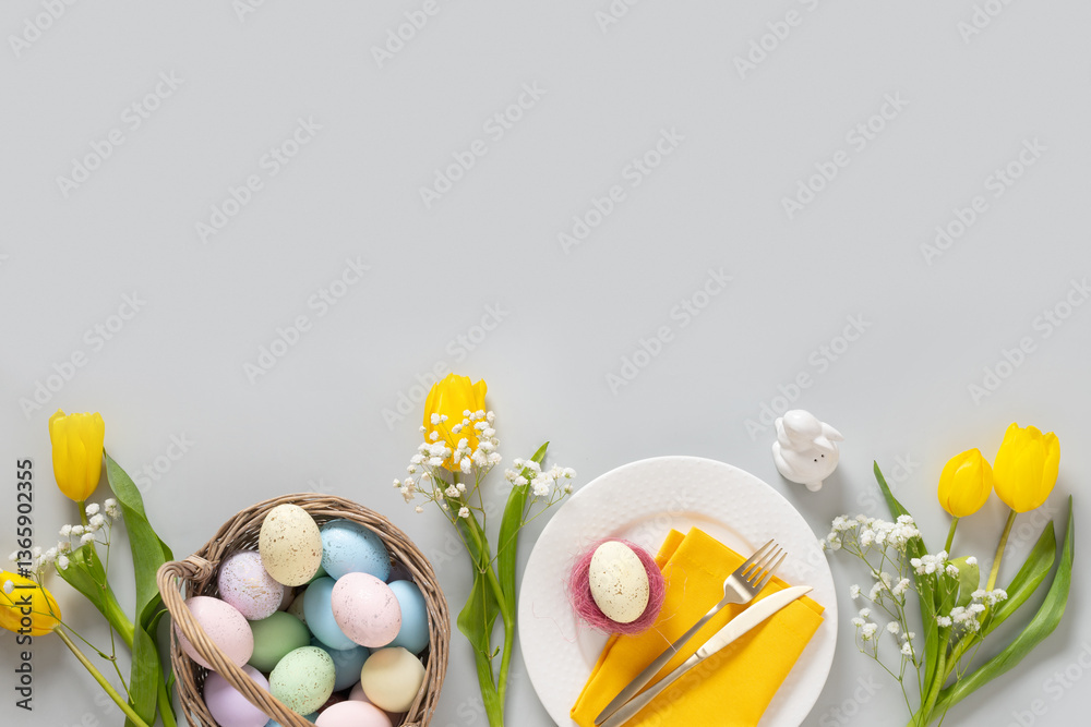 Easter frame with pastel yellow eggs, tulip flowers, gypsophila and yellow chick on gray background. View from above. Flat lay. Happy Easter greeting card.