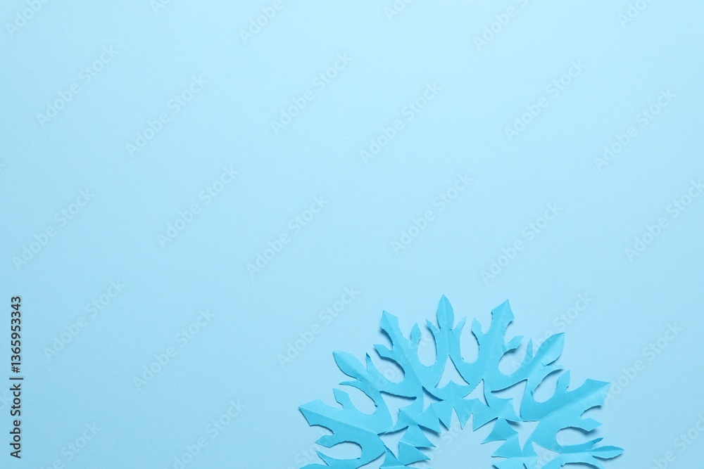 One beautiful paper snowflake on light blue background, top view. Space for text