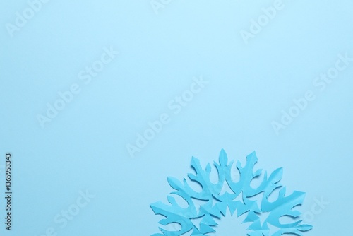 One beautiful paper snowflake on light blue background, top view. Space for text