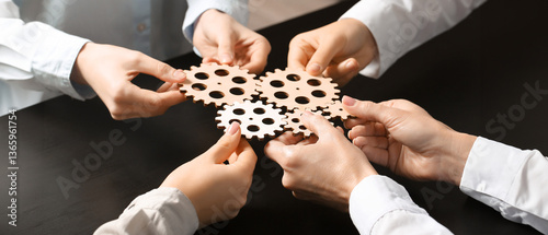 Group of business people holding wooden gears at table