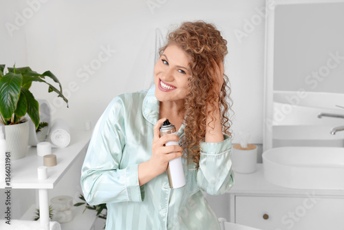Hair care and beauty routine, young woman applying hairspray to curly hair in...