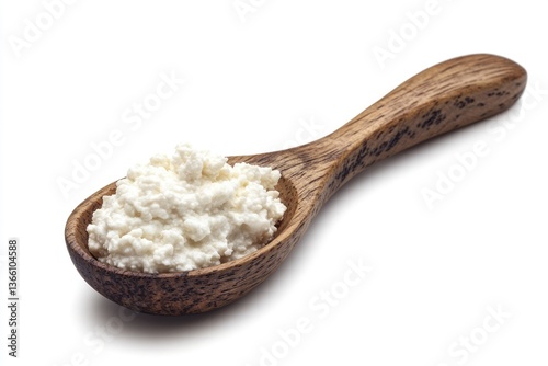 A wooden spoon holds a spoonful of creamy, fresh cottage cheese, isolated on white.