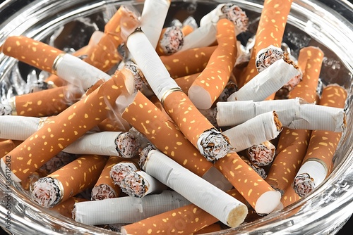 Pile of extinguished cigarettes resting inside a glass ashtray photo