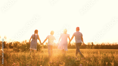 Children are having fun playing in a forest glade. Summer time of childhood. small children. A girl, a boy, classmates, holding hands, go into the sunset. A friendly team of kindergarten children. The