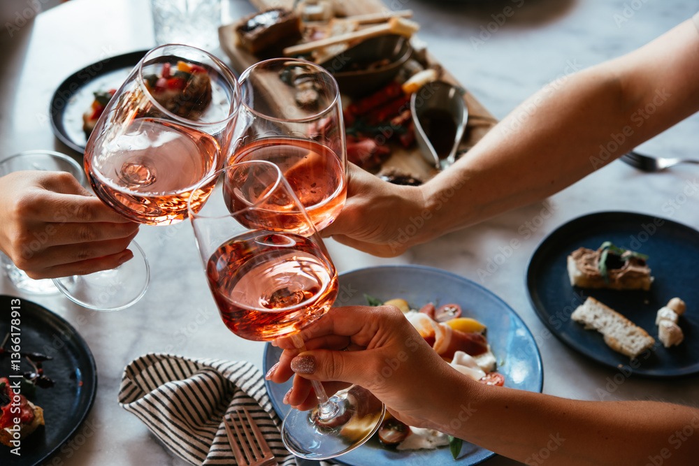 Friends having a dinner party with different kinds of appetizers and rose wine.