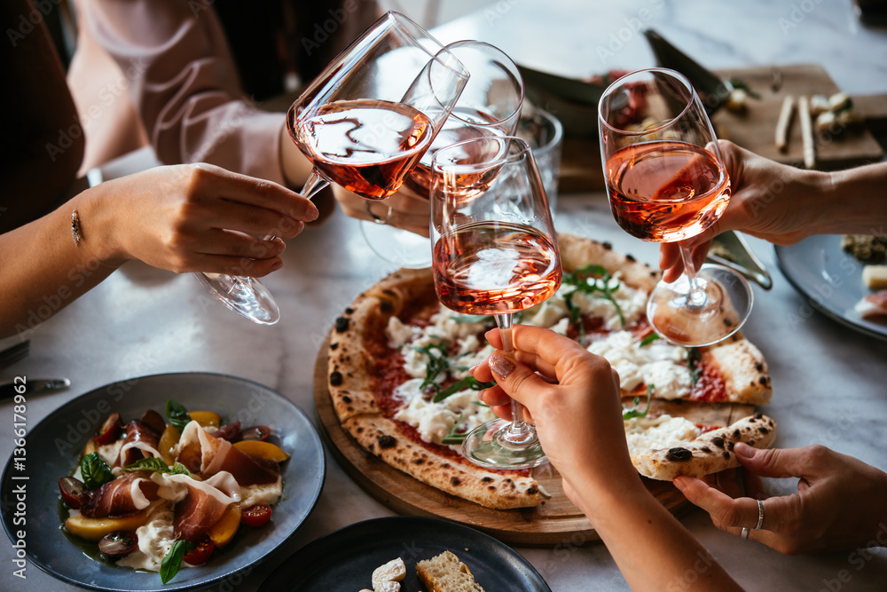 Friends enjoy a dinner party with pizza and rose wine in a bar or a restaurant.