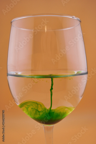 Colored water dropping into a wine glass filled with water.