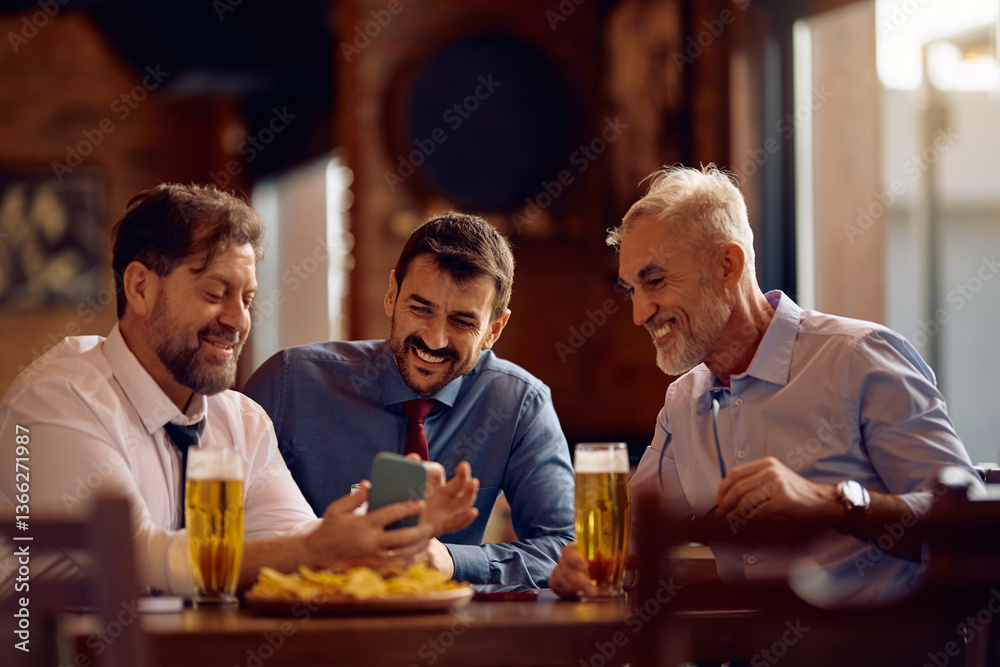 Happy colleagues using app on smart phone while gathering for drink in pub. Happy colleagues using app on smart phone while gathering for drink in pub.