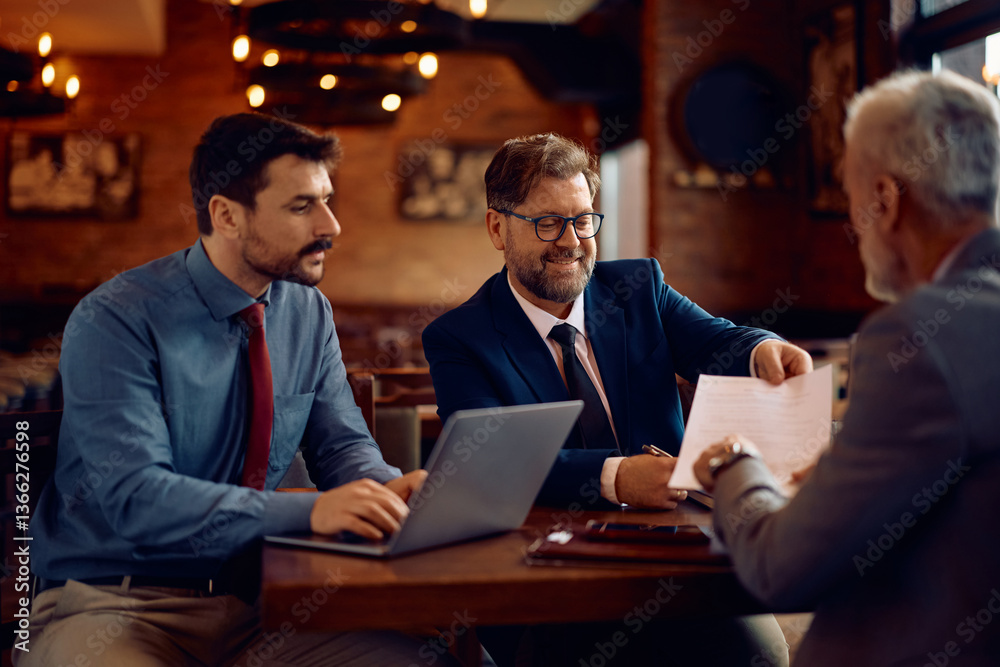 Team of entrepreneurs analyzing business plans while gathering for meeting in pub. Team of entrepreneurs analyzing business plans while gathering for meeting in pub.