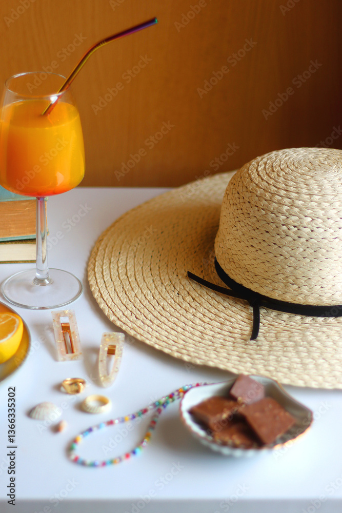Glass of cocktail, straw hat, sunglasses, books, fresh fruit, chocolate and accessories. Summer essentials on the table. Selective focus.