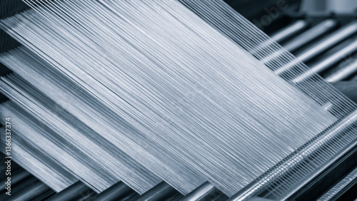 A machine is weaving a piece of fabric. The machine is made up of many parts, including a large metal piece that is connected to a hose
