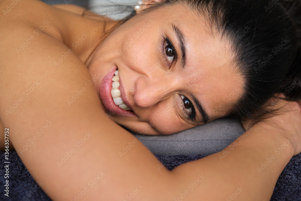 Happy latin woman lying on a massage table, enjoying a relaxing treatment