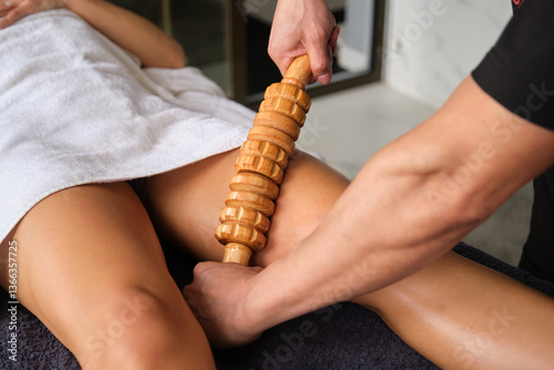 Obraz na płótnie Therapist applying maderoterapia massage technique on female client leg with wooden rolling pin w salonie