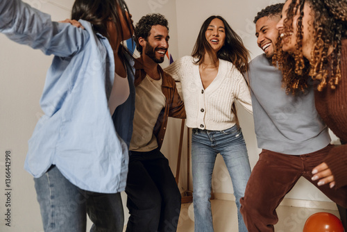 A multinational group of young adults are dancing and having fun together in a lively indoor setting, while sharing laughter and enjoying a joyful moment with friends and positive energy.