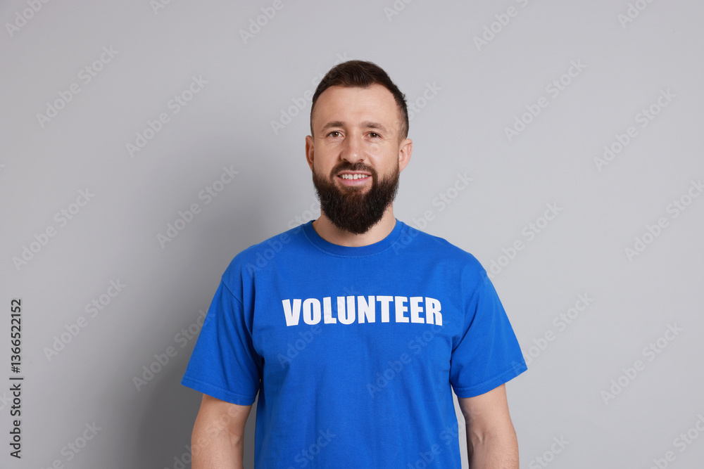 Obraz premium Positive man wearing t-shirt with word Volunteer on light grey background